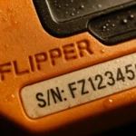 Detalle de un dispositivo naranja con la palabra "FLIPPER" y número de serie visible.