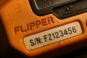 Flipper Zero: Análisis de las supuestas vulnerabilidades en sistemas automotrices modernos Detalle de un dispositivo naranja con la palabra "FLIPPER" y número de serie visible.