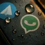 Auf einem dunklen Hintergrund befinden sich die Symbole von Telegram und WhatsApp, umgeben von Wassertropfen.