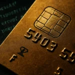 Close-up of a gold credit card showcasing the chip and embossed numbers.