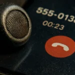 Close-up of a phone call interface with headset, showing caller ID and duration.