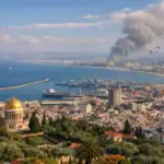 Coastal cityscape with a golden dome and smoke rising in the background.