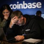 Employee shows concern while another focuses on a laptop in a dimly lit office.