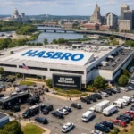 Aerial view of Hasbro building with maintenance sign and city skyline nearby.