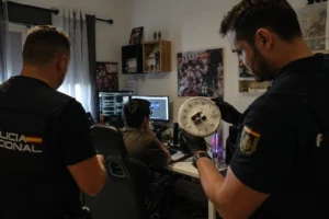 Two officers investigate a computer setup in a room, examining a clock.