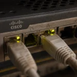 Netzwerkanschlüsse eines Cisco-Routers mit leuchtenden LEDs.