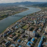Aerial view of a river separating North Korea and Russia, with urban landscapes.